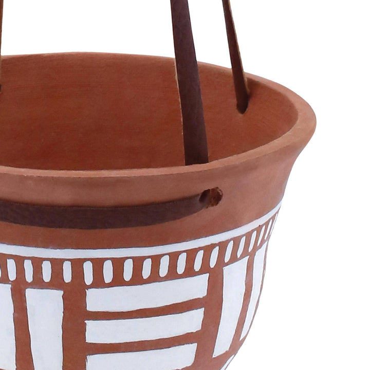 Terracotta pot with white decorative pattern on a white background