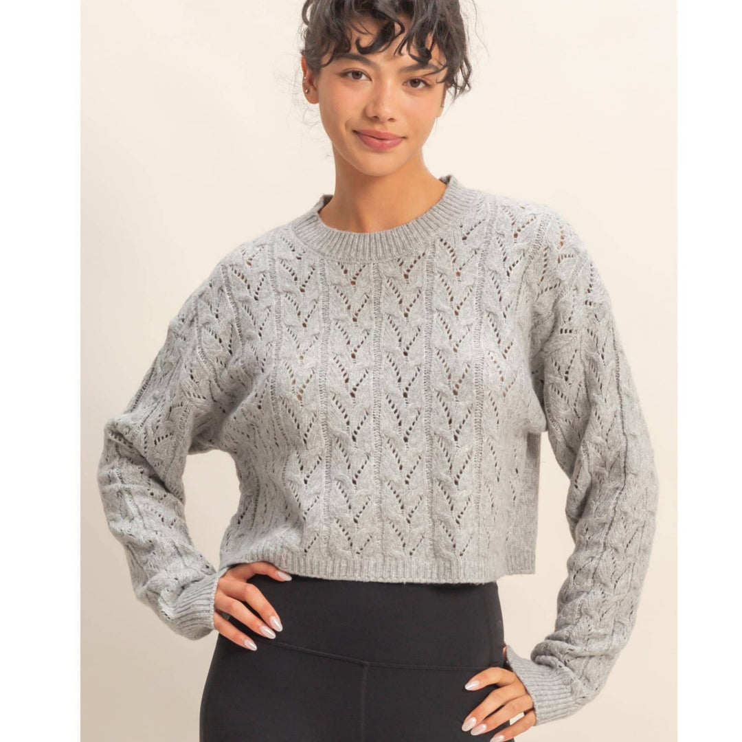 Woman wearing a gray patterned sweater against a beige background